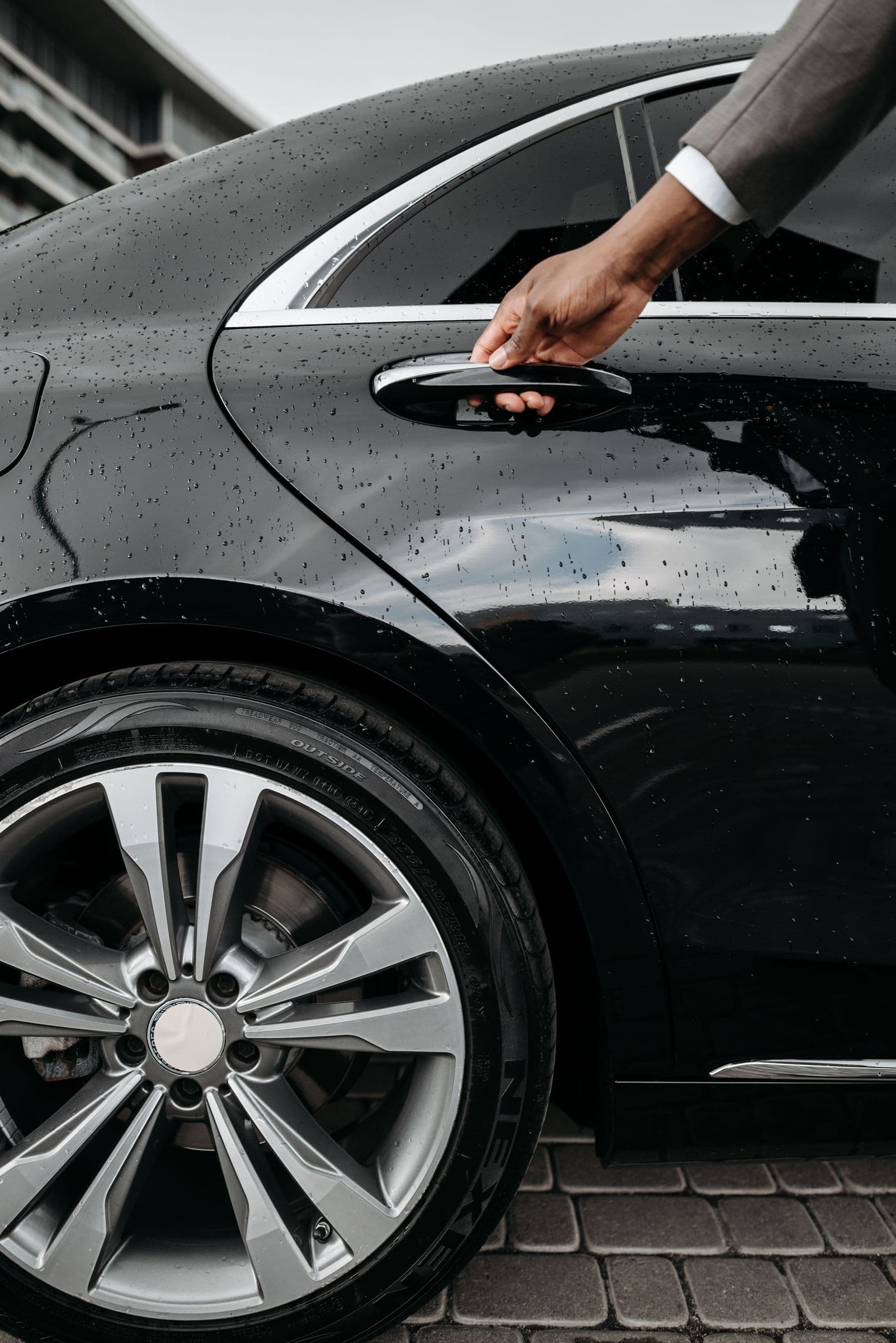 A chauffeur opening the door of a black car