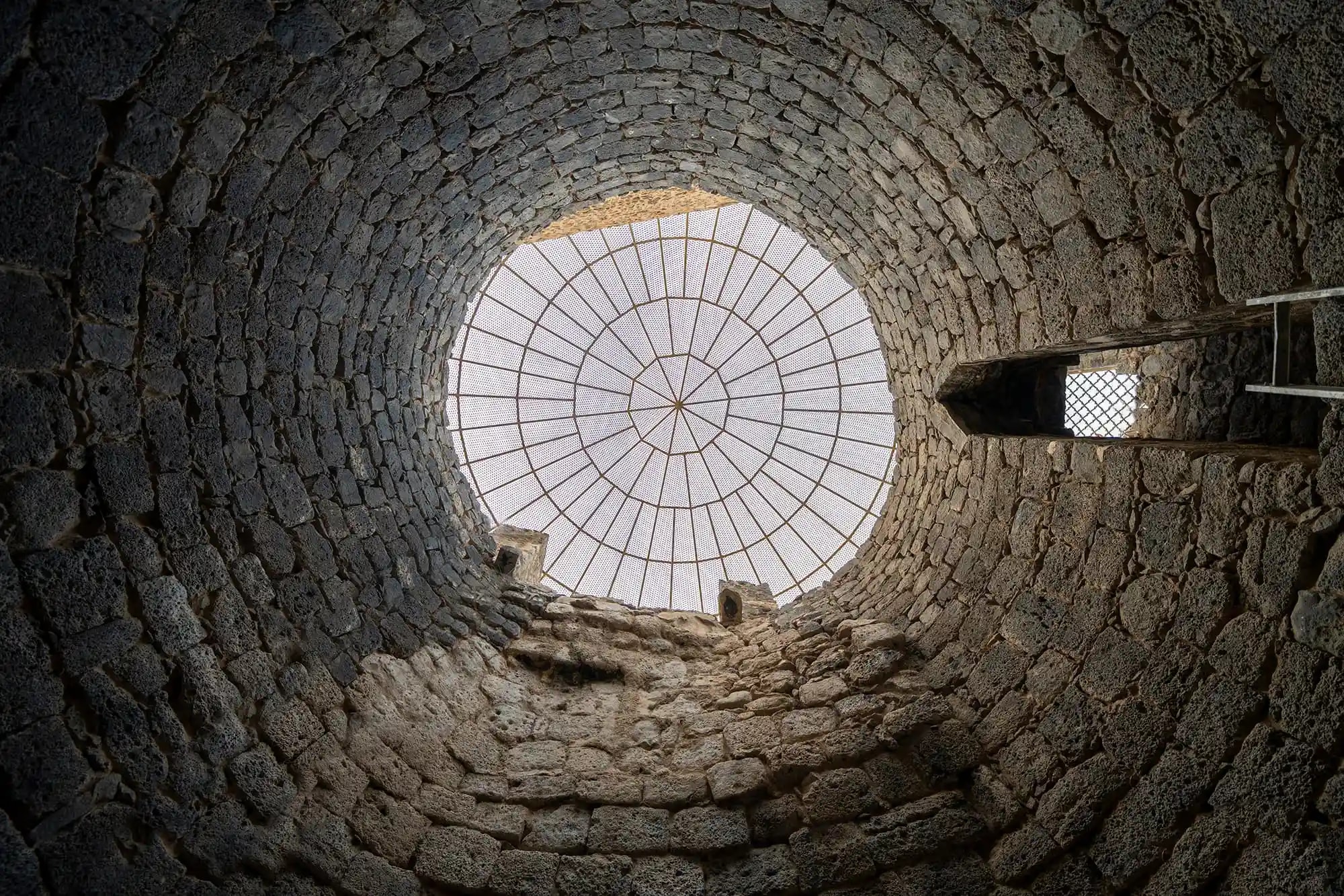 Looking up at the latticed dome over Bi'r Ghars, a historic well in the Quba orchards