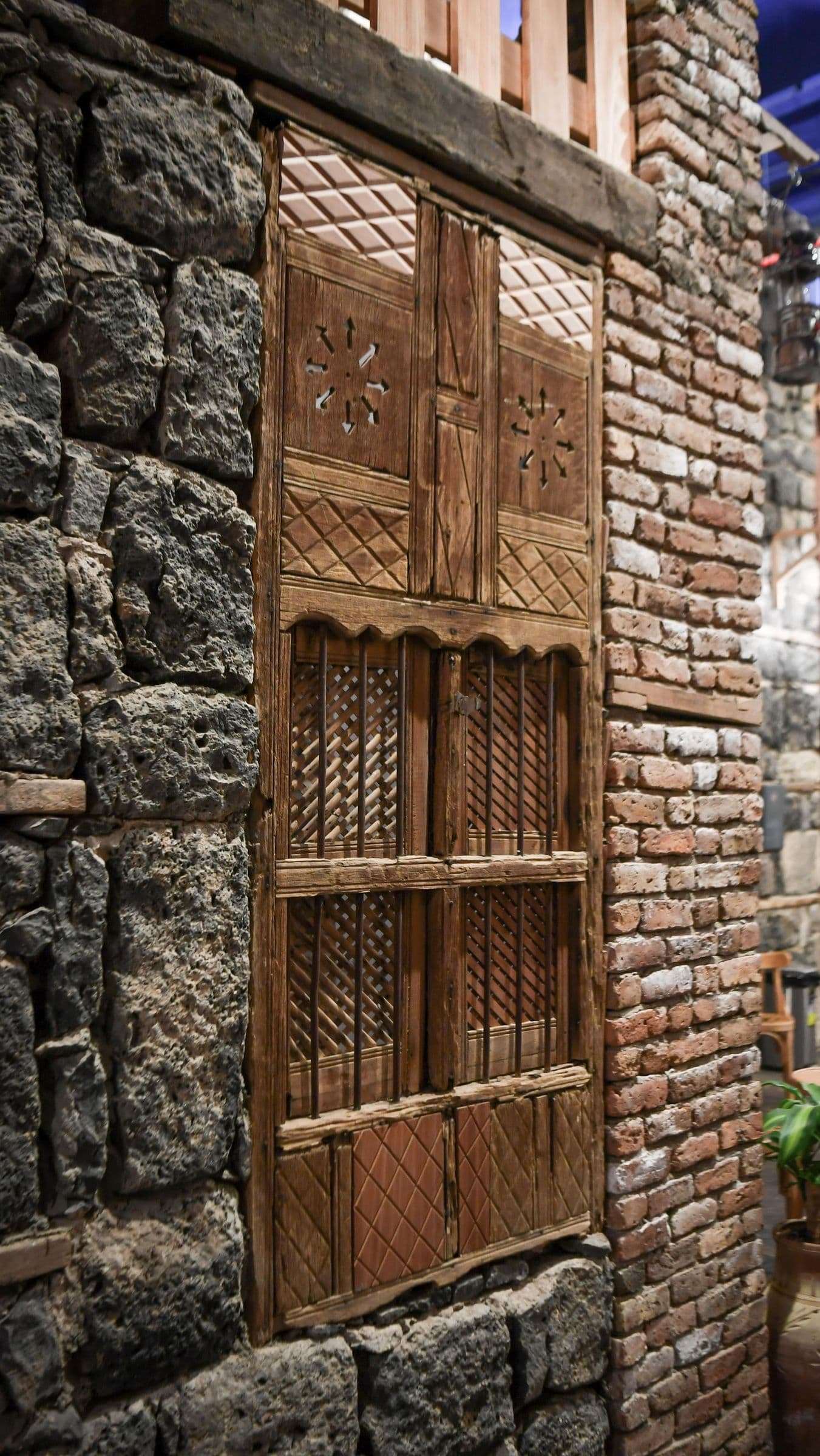 Carved wooden rawasheen window on a historic Madinah stone house (heritage detail)